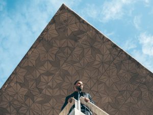 Man in suit on balcony under geometric canopy