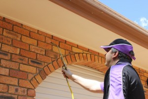 Worker spraying exterior brick near eaves