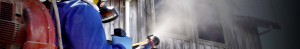 Worker fogging pesticide at wooden building
