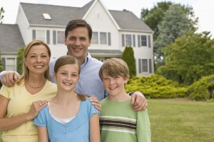 Smiling family of four in front of house