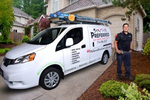Pest control technician beside service van in driveway