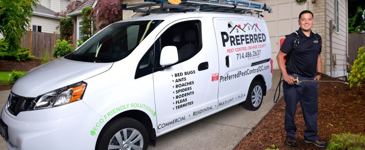 Pest control technician beside service van in driveway