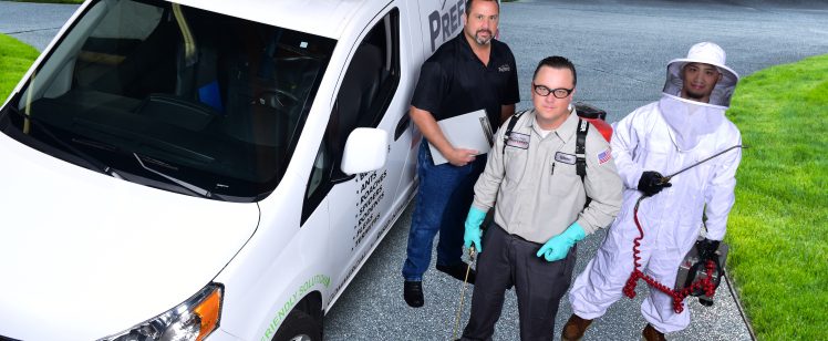 Pest control technicians beside service van