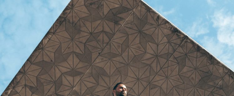 Man in suit on balcony under geometric canopy