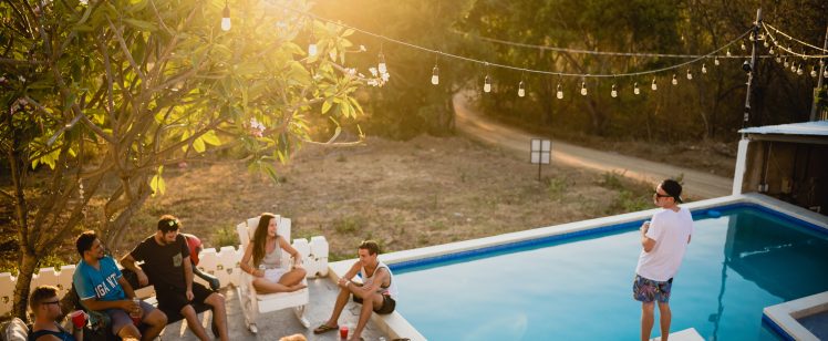 Friends gathering by pool at sunset with lights
