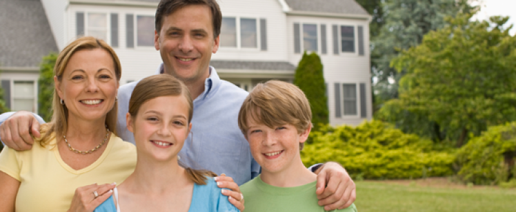 Smiling family of four outside house