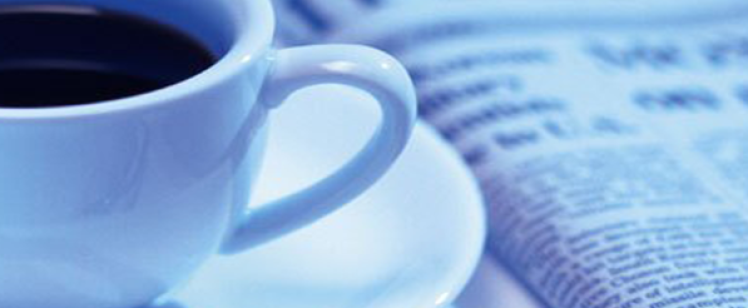 Cup of coffee beside folded newspaper