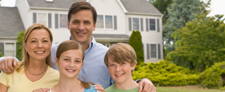 Family of four outside suburban house