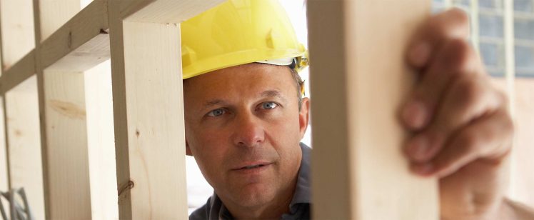 Construction worker inspecting wooden wall framing